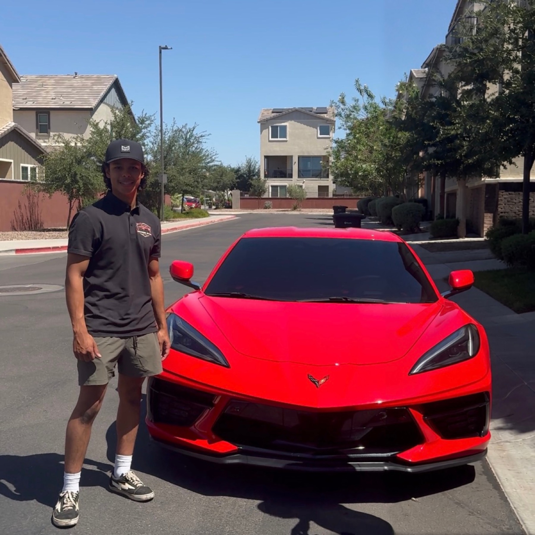 Noah Sanchez standing next to a red Corvette after detailing